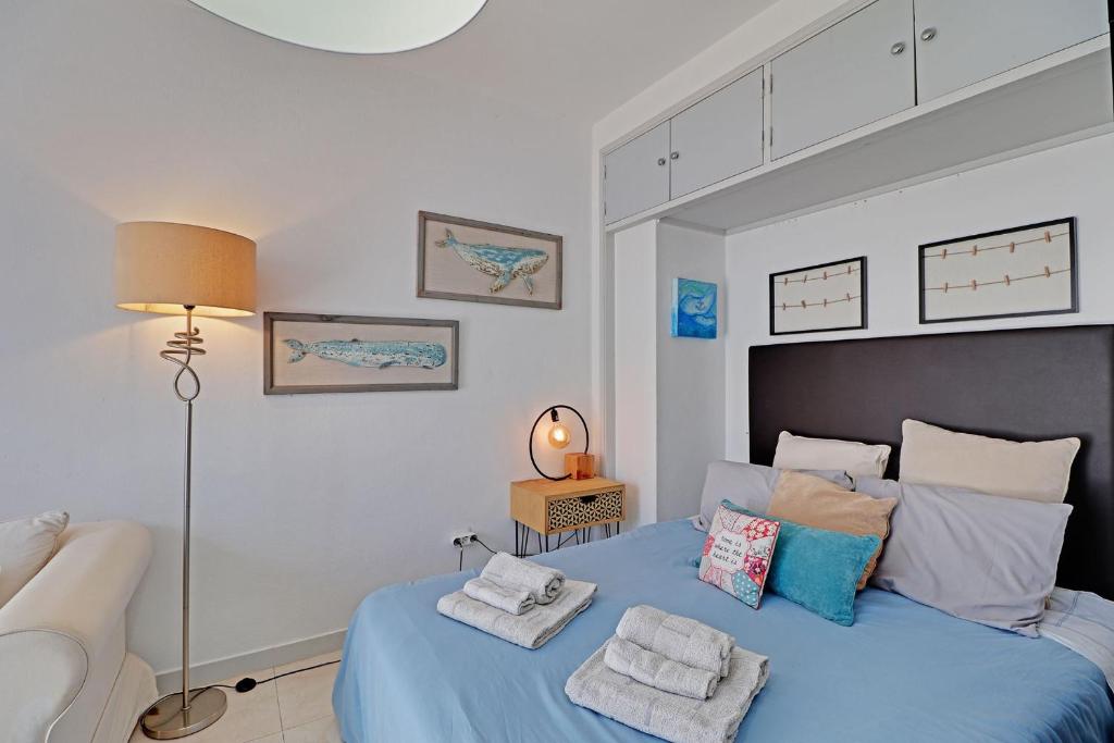 a bedroom with a blue bed with towels on it at Faro Airport Flats by Homing in Faro
