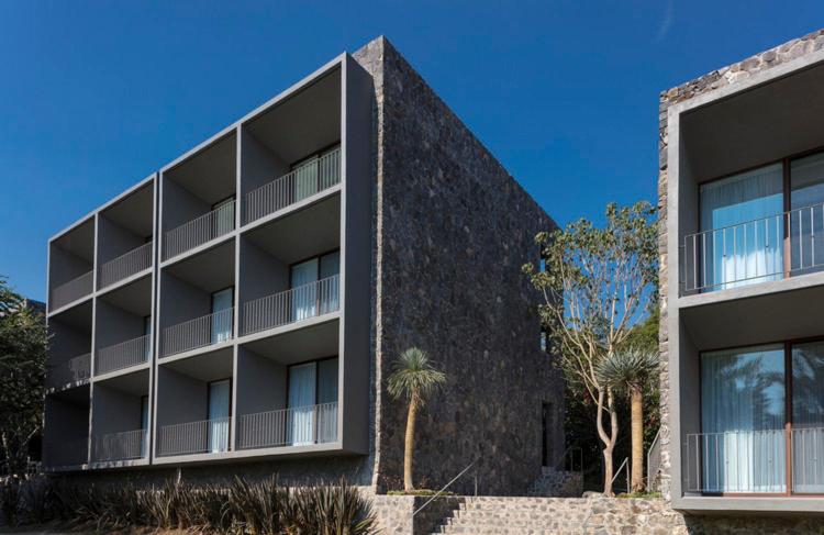 um edifício de apartamentos com uma fachada negra e palmeiras em Huayacán Cuernavaca Curamoria Collection em Jiutepec