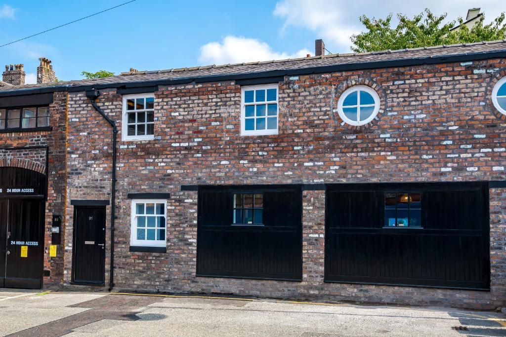 an old brick building with three garage windows at Host & Stay - The Roscoe Carriage House in Liverpool