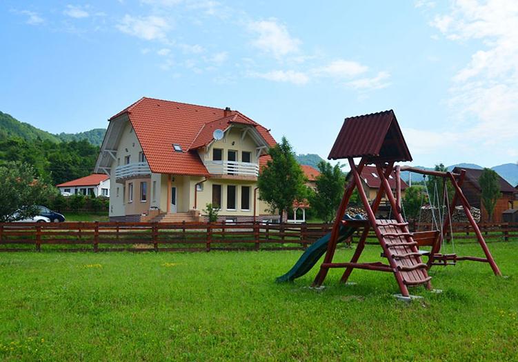 un parque infantil con un tobogán en un patio con una casa en Halasto Pension, en Praid