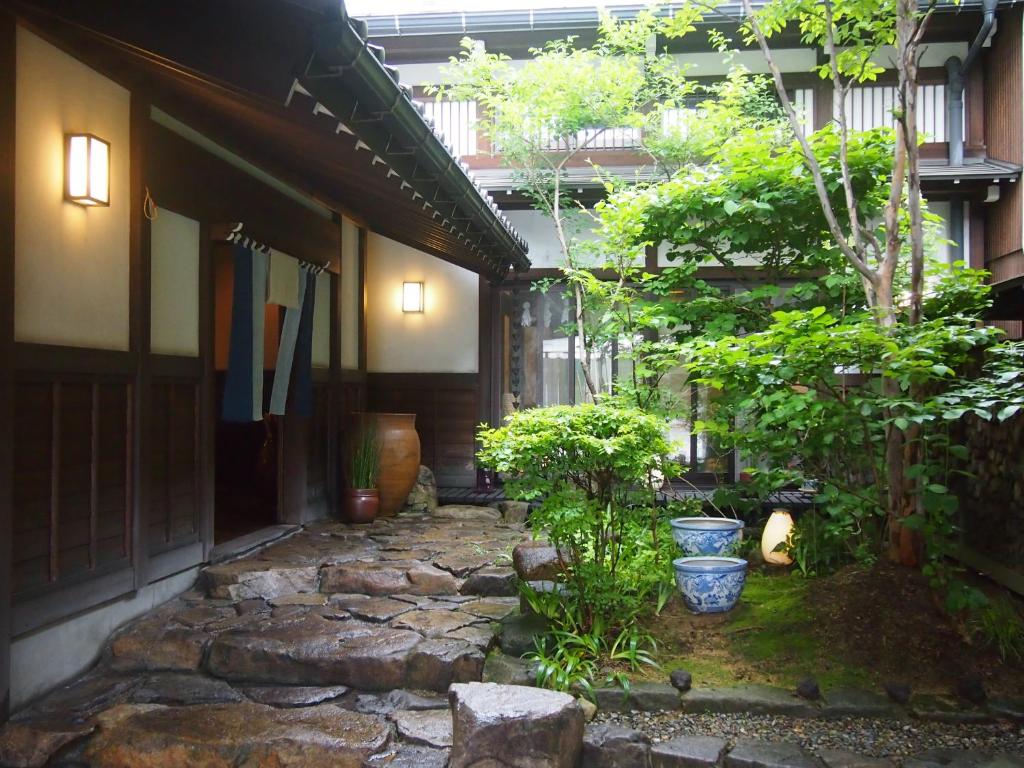 a stone walkway in front of a building with plants at Oyado Koto No Yume in Takayama
