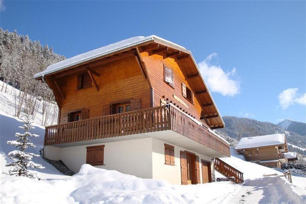 un gran edificio de madera con un balcón en la nieve en Les Fledd's, en La Chapelle-dʼAbondance