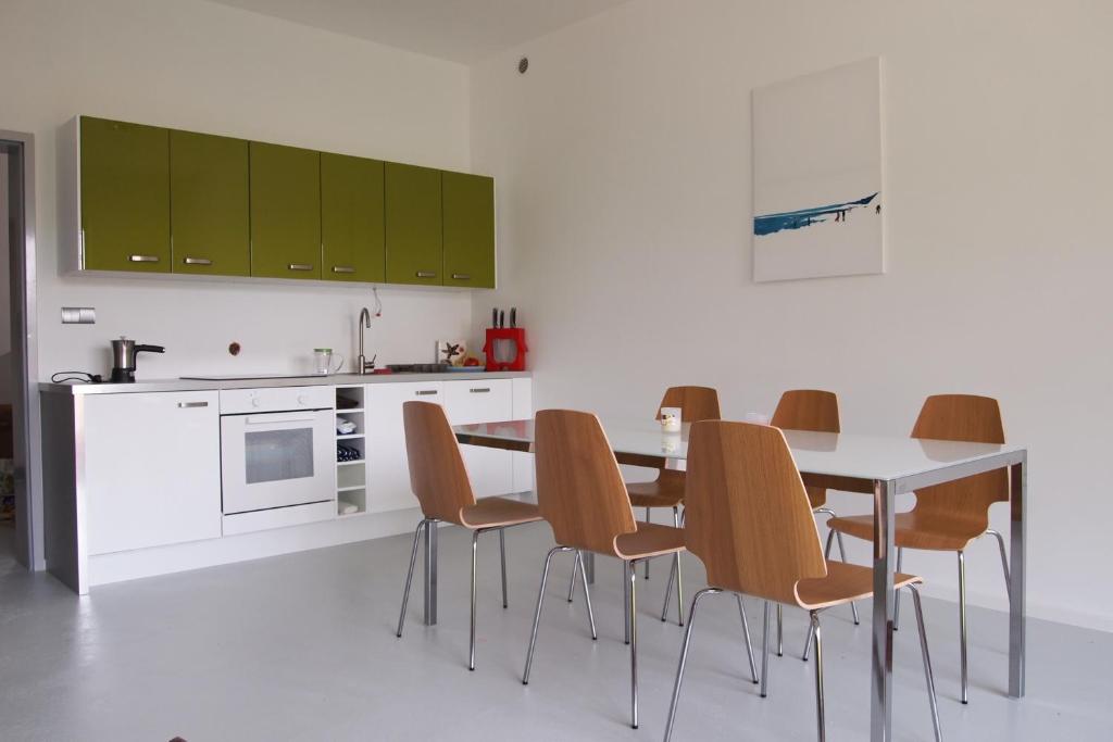 una cocina con mesa, sillas y armarios verdes en Apartamenty Poli House, en Krynica Morska