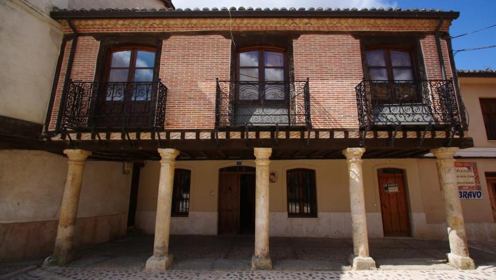 an old building with a balcony and a building at Casa Rural Plaza Vieja Saldaña in Saldaña