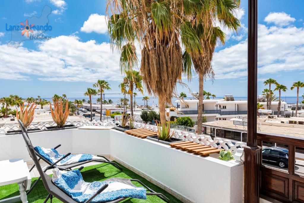 patio z krzesłami i palmami na balkonie w obiekcie Vivienda Vacacional Timanfaya w Puerto del Carmen