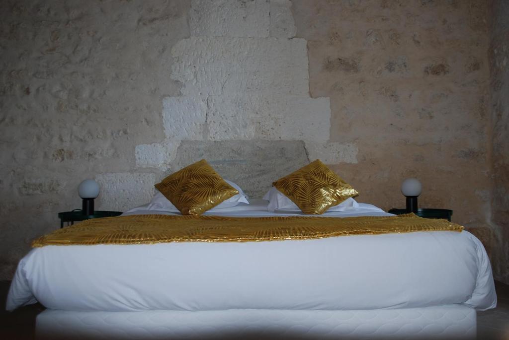 a bedroom with a white bed with gold pillows at Champ Fleuri in Angoulême