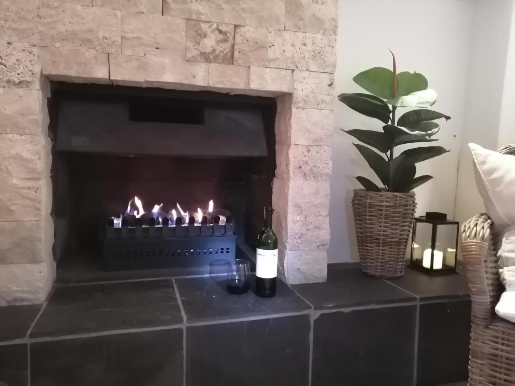 a fireplace with a bottle of wine and candles at African Violet Guest Suites in Noordhoek