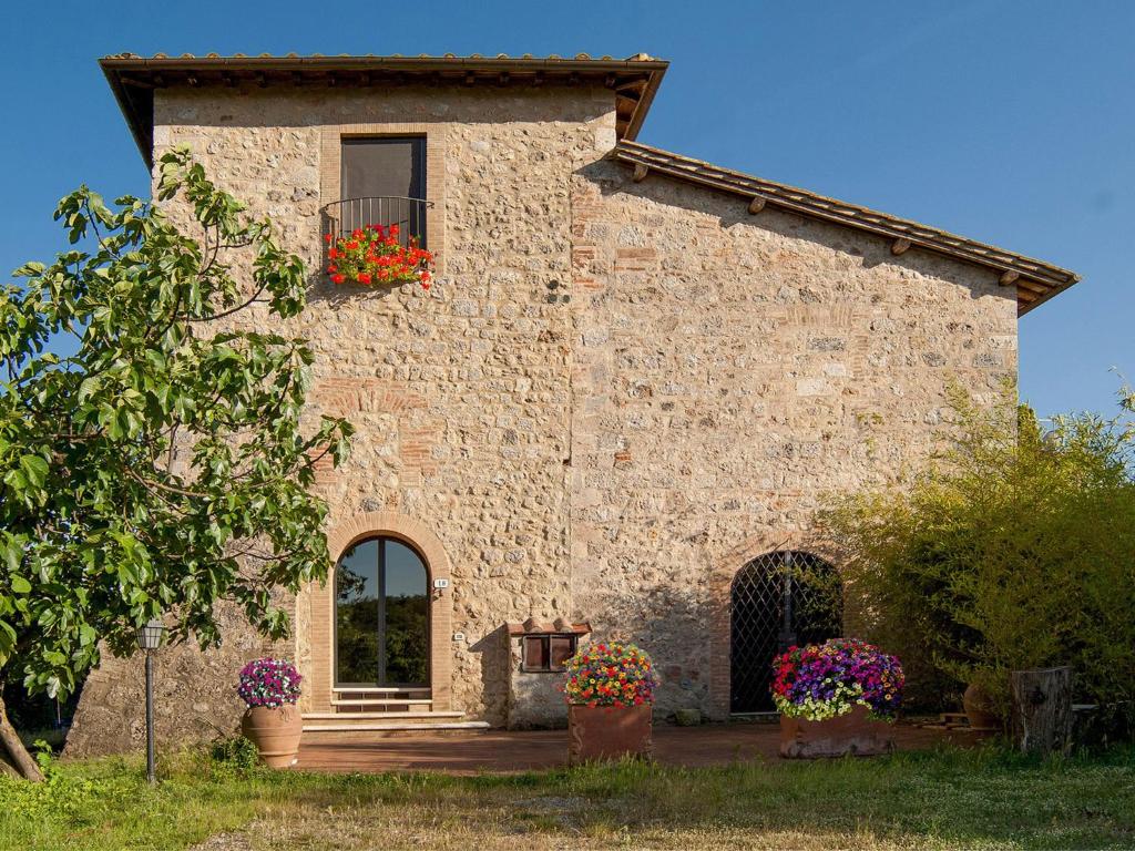 a stone building with a window and flower boxes on it at Torre Della Chiocciola in Monteriggioni