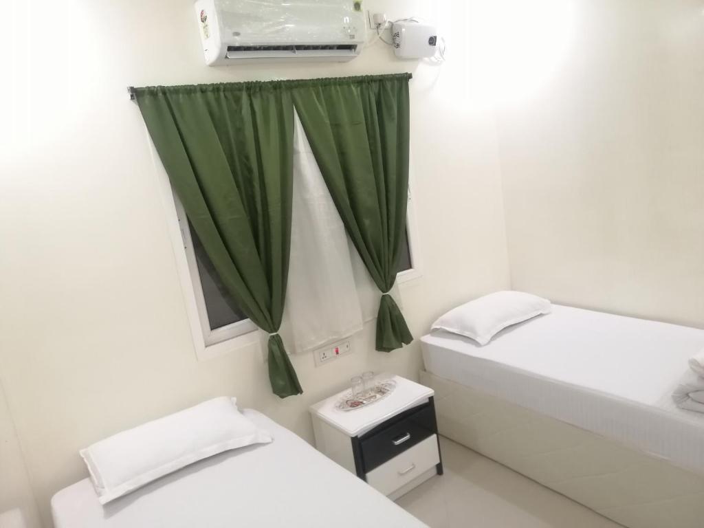 ein Badezimmer mit 2 Betten und einem grünen Vorhang in der Unterkunft RAJHAT MARANAO House in Bodh Gaya