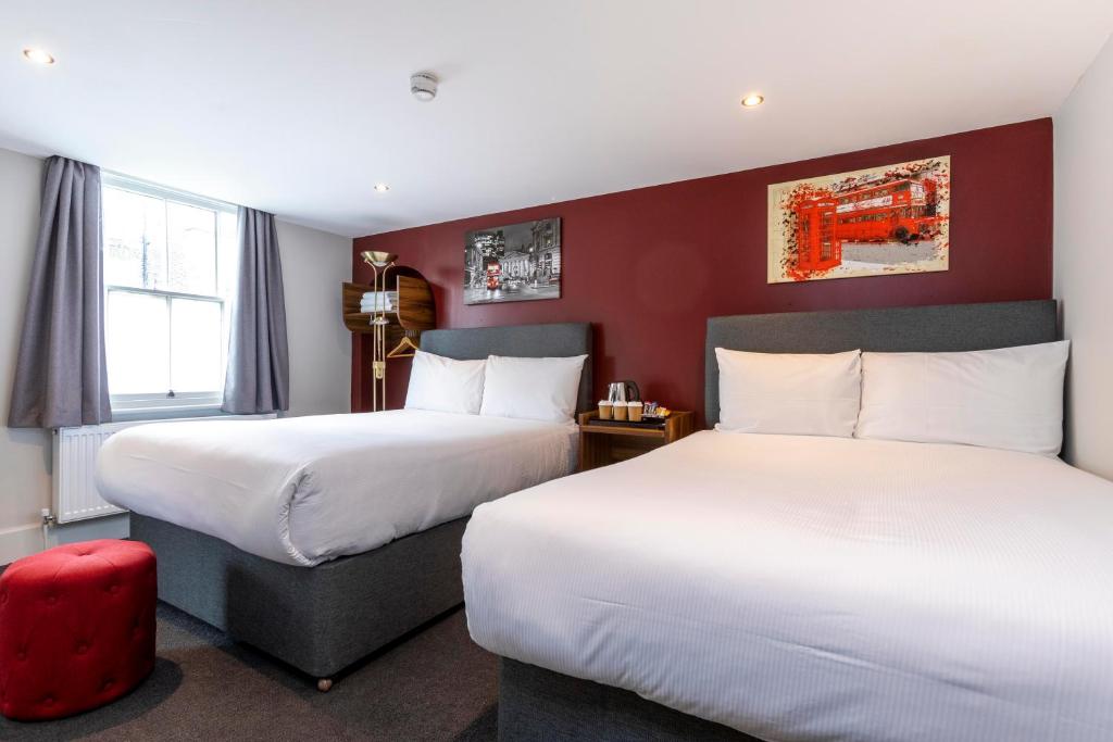 een hotelkamer met 2 bedden en een rode muur bij Royal Park Hotel in Londen