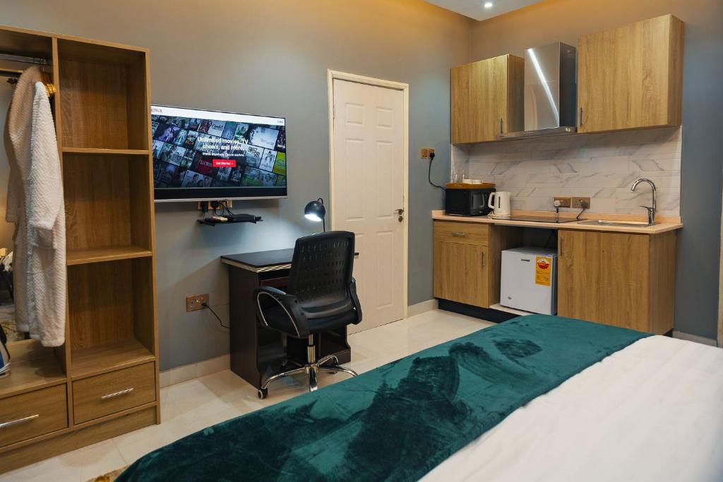 阿克拉The Avery Suites, East Legon的一间卧室配有一张床、一张书桌和一台电视