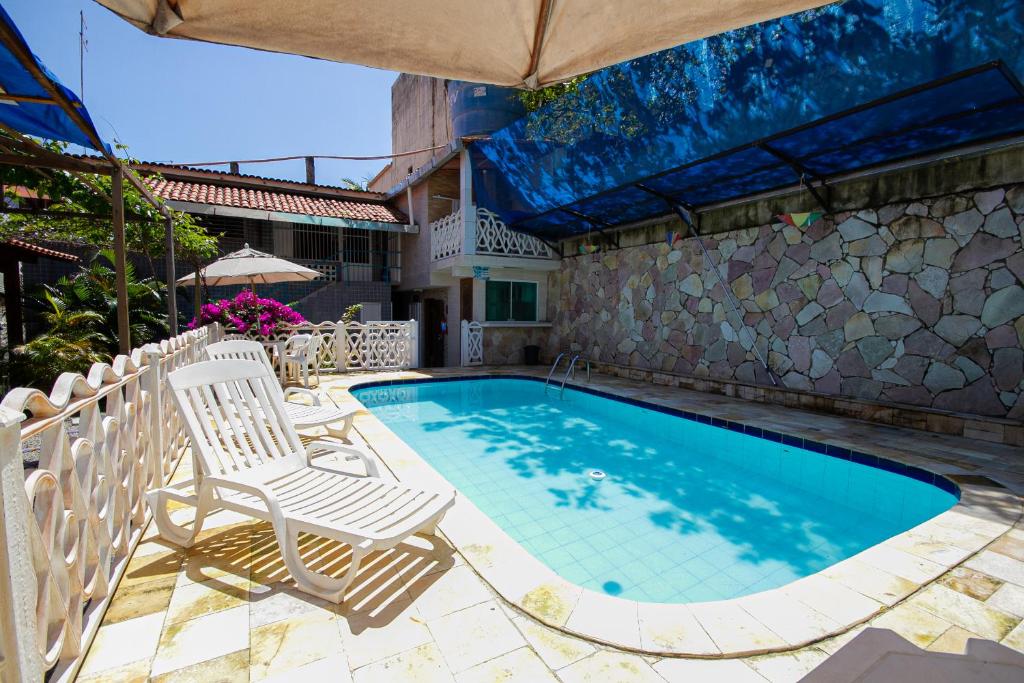 a swimming pool with two chairs and an umbrella at Pousada Santa Fé in Porto De Galinhas