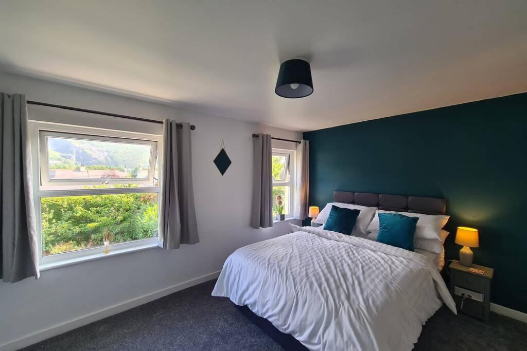 a bedroom with a large bed and two windows at Minafon in Llanberis