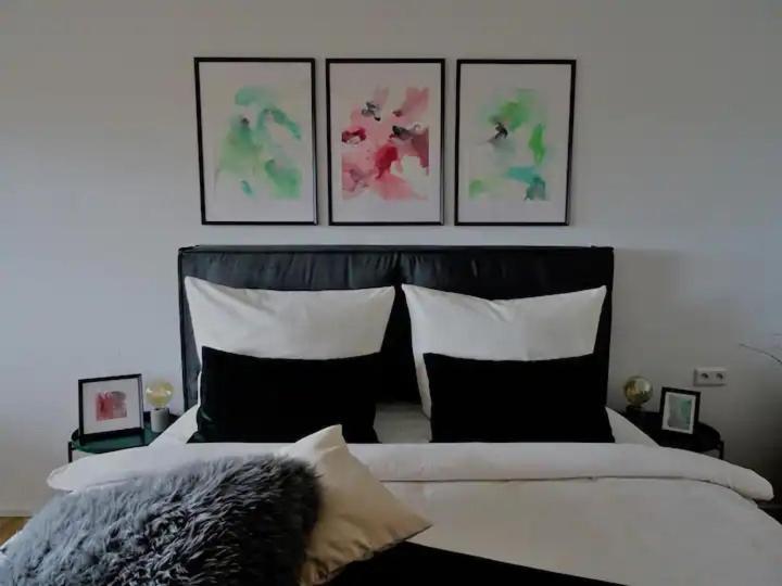 a bedroom with a bed with four paintings on the wall at Modernes Apartment mit Traumhaftem Blick ins Grüne in Bräunlingen