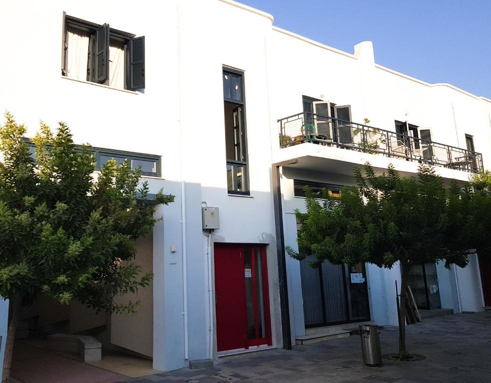 a white building with a red door and trees at Trianon in Paphos City