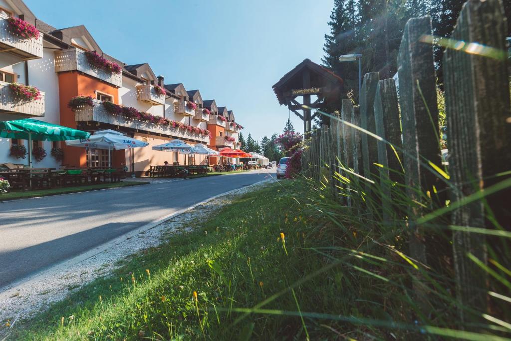 una calle con una valla y algunas mesas y sombrillas en Hotel Jakec Trije kralji na Pohorju, en Zgornja Ložnica