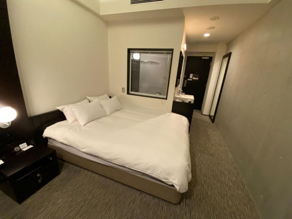 1 dormitorio con 1 cama con sábanas y almohadas blancas en ＦＵＲＡＮＯ ＮＡＴＵＬＵＸ ＨＯＴＥＬ - Vacation STAY 68187v, en Furano