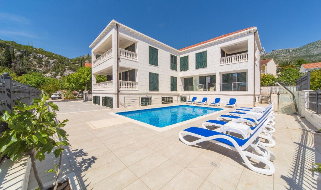 a house with a swimming pool and lounge chairs at Apartments Casa Blanca y Verde in Slano