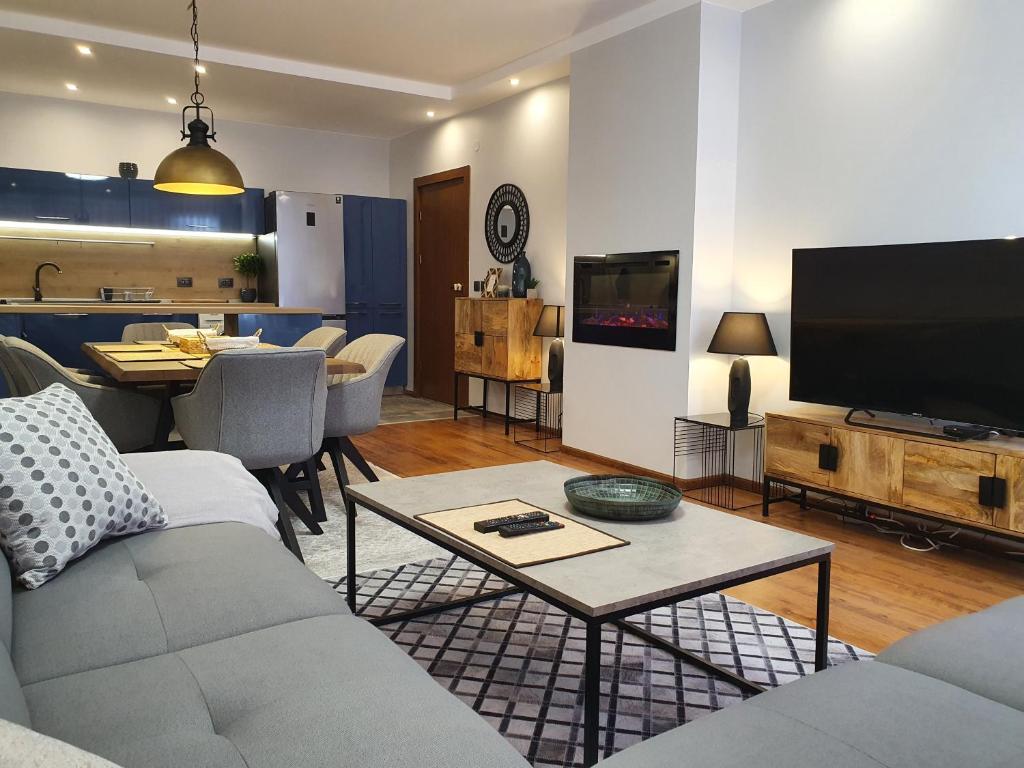 uma sala de estar com um sofá, uma televisão e uma mesa em Monteverde Ski Lift Apartment Bansko em Bansko