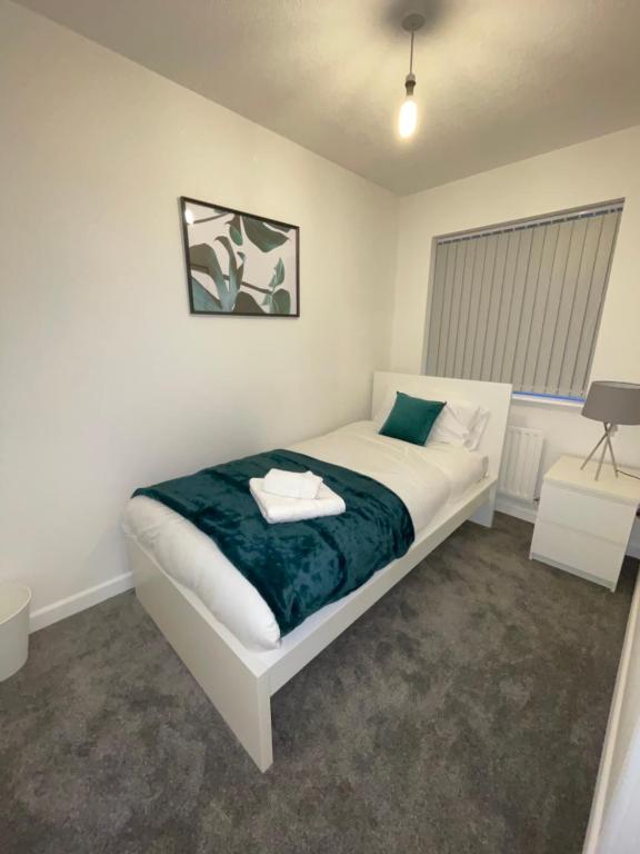 Un dormitorio con una cama blanca con una manta verde. en Modern 2 bed house Cannock Driveway for 2 vehicles Perfect for contractors Business Travellers Short Stays Close to M6 M54 i54 A5 A38 McArthur Glen Designer Outlet, en Cannock