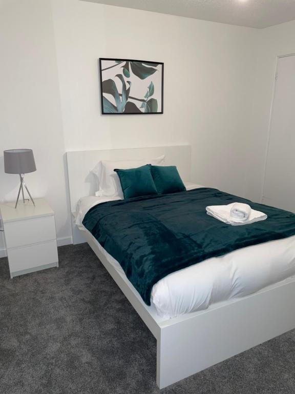 a bedroom with a white bed with a green blanket at Cannock, Modern 2 bed house, Perfect for contractors, Business Travellers, Short Stays, Driveway for 2 vehicles, Close to M6, M54/i54, A5.A38. McArthur Glen Designer Outlet in Cannock