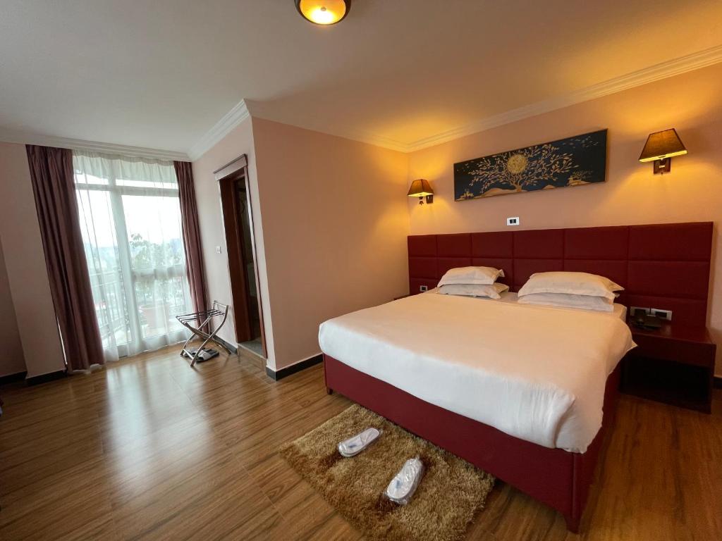 a bedroom with a large bed and a large window at Moonlight Hotel Addis Ababa in Addis Ababa