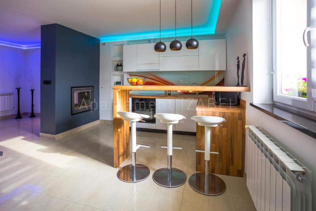 a kitchen with three bar stools in a room at Apartament Izabel in Nowy Targ