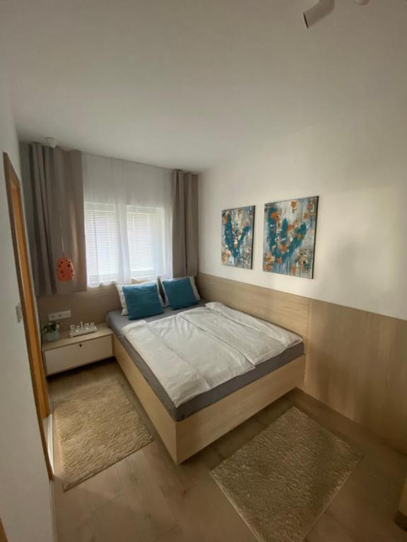 1 dormitorio con 1 cama grande con almohadas azules en MAXIM Apartments, en Harkány
