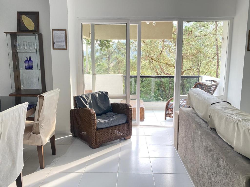 a living room with a couch and chairs and a window at Apartamento até 10 pessoas na enseada Guarujá em condomínio clube praia piscinas salão jogos quadra futebol campo parquinho brinquedos Wi-fi Home office in Guarujá