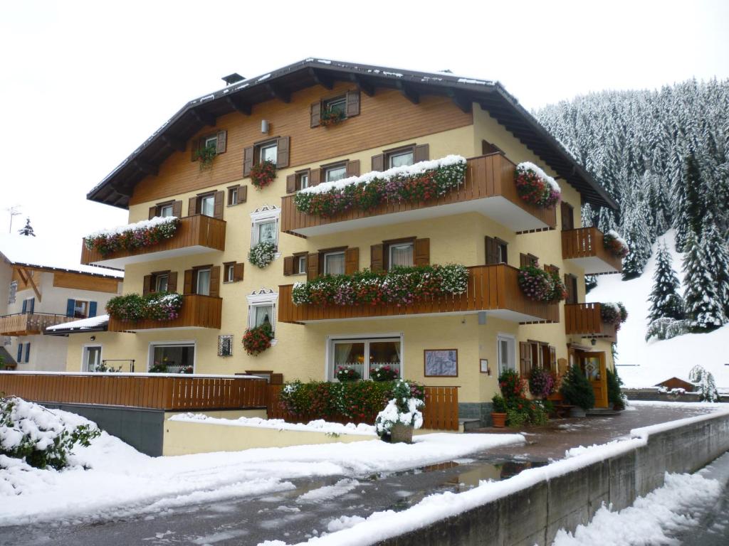 Un bâtiment avec des fleurs sur son côté dans la neige dans l'établissement Hotel I Rododendri, à Valfurva