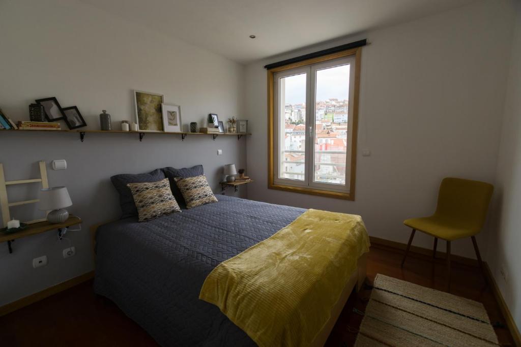 um quarto com uma cama, uma janela e uma cadeira em Avenida Central - Coimbra Accommodation em Coimbra