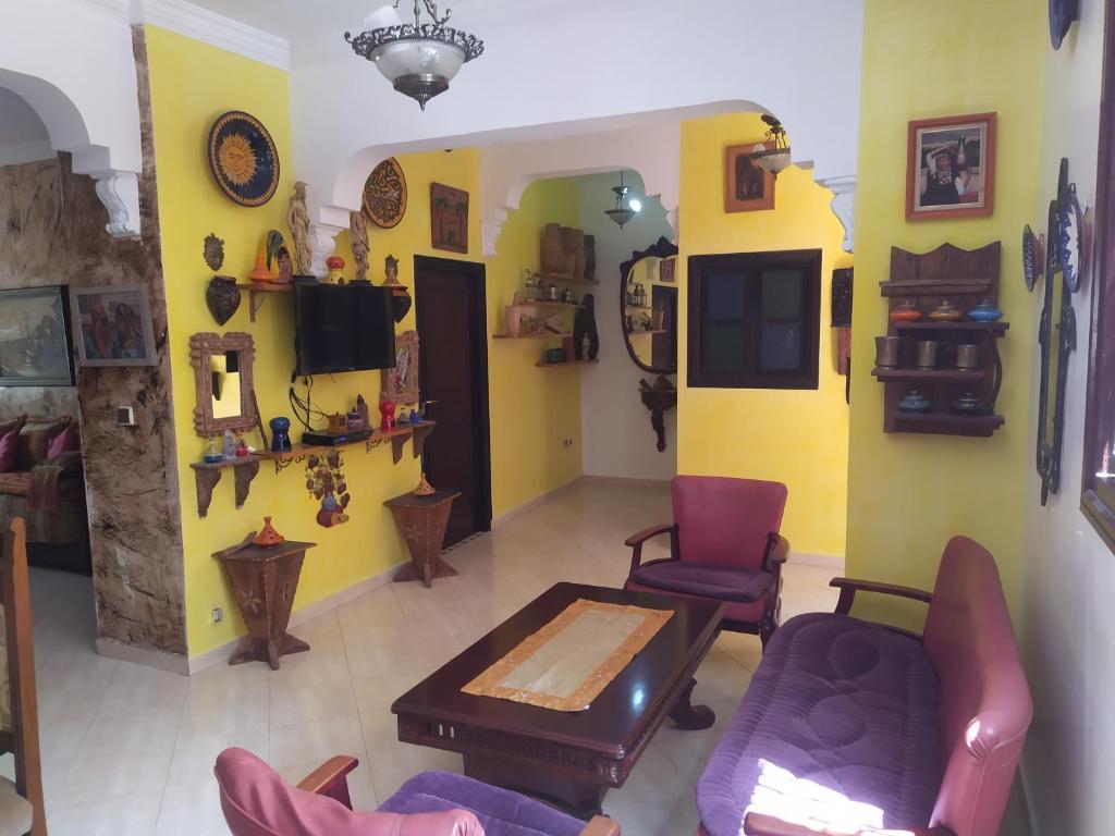 sala de estar con sillas, mesa y paredes amarillas en Marguerite Apartemnt dans une résidence familiale, en Casablanca