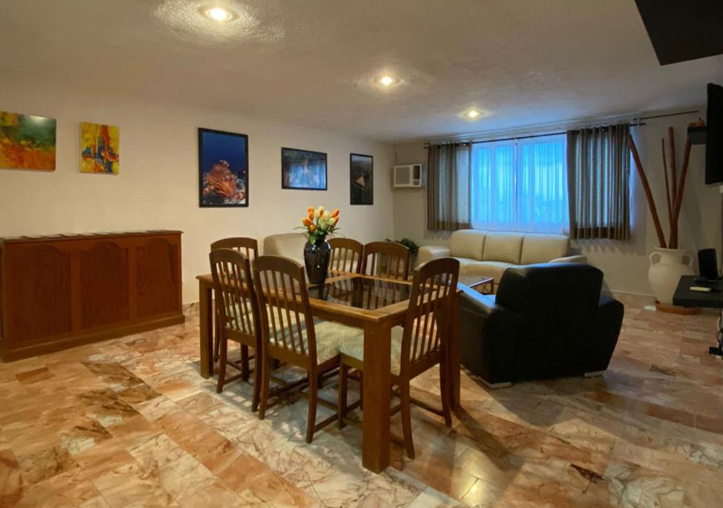 ein Wohnzimmer mit einem Tisch, Stühlen und einem Sofa in der Unterkunft Departamento Deli in Cancún