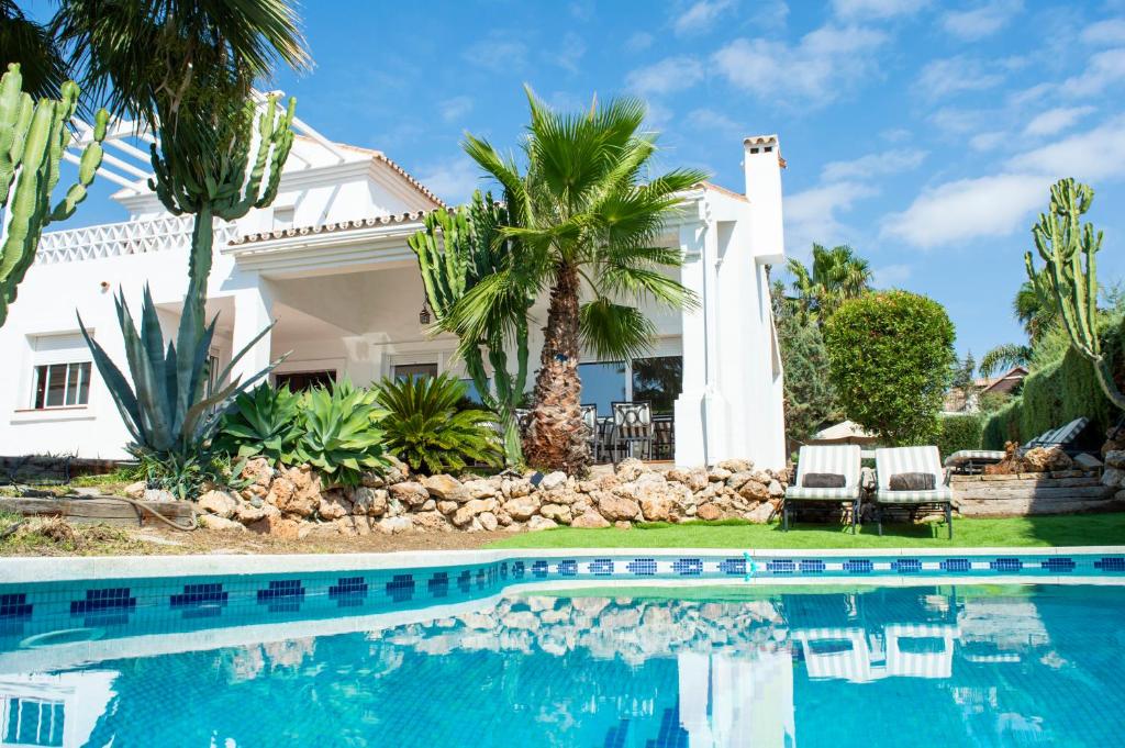 a house with a swimming pool and palm trees at Villa Bendex Estepona Costa Del Sol in Estepona