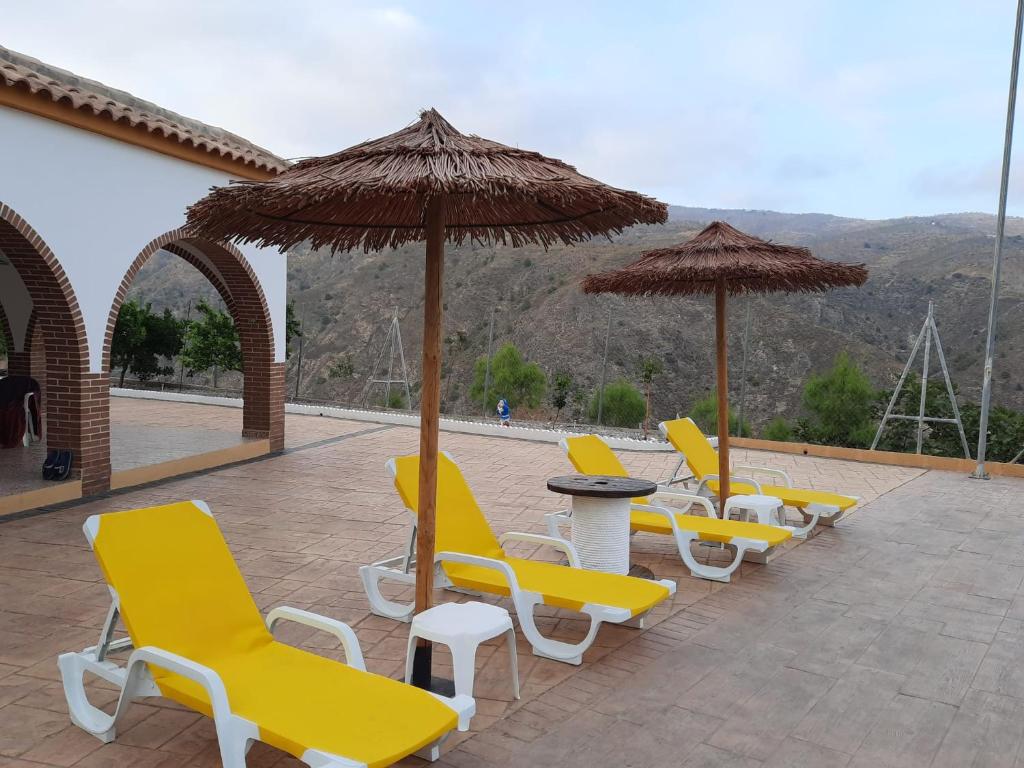 una fila de sillas y sombrillas amarillas en un patio en Benavilla en Albuñol