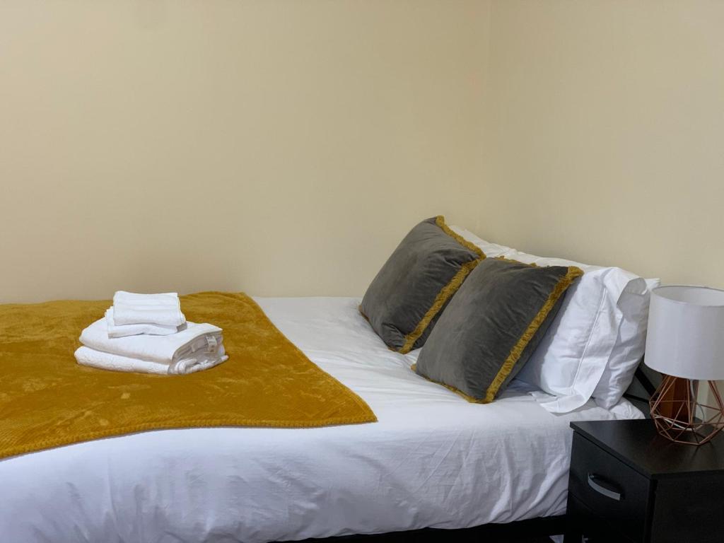 een bed met twee kussens en een handdoek erop bij Beautiful 5 Bedroom Home to Enjoy in Ilford
