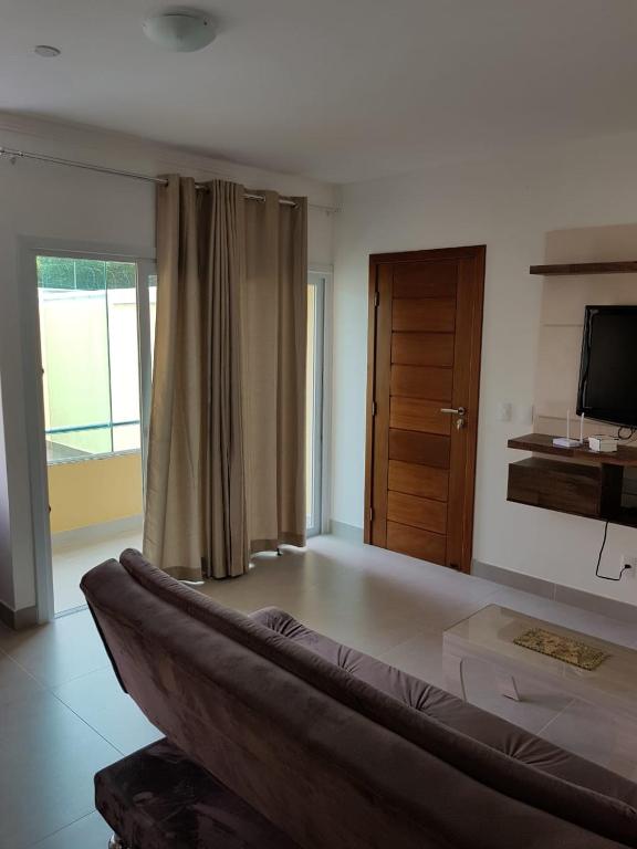 ein Wohnzimmer mit einem Sofa und einem TV in der Unterkunft Apartamento Beira-Mar, Paraíso dos Pataxós. in Porto Seguro