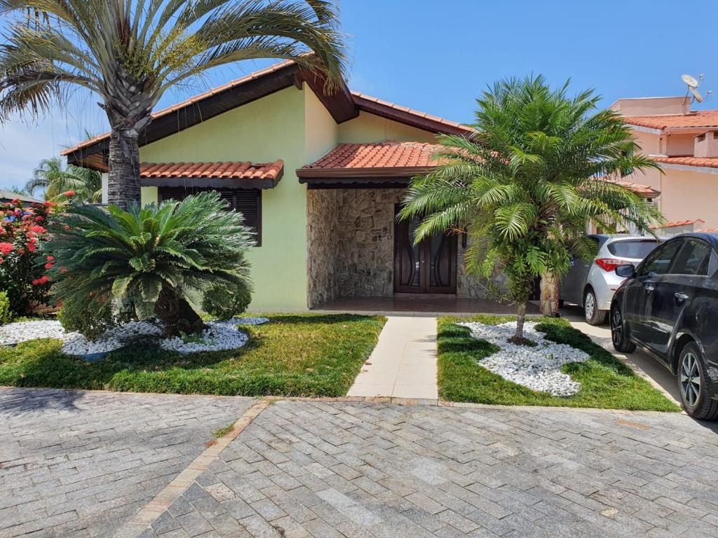 a house with two palm trees and a driveway at Casa Morada da Praia in Boracéia