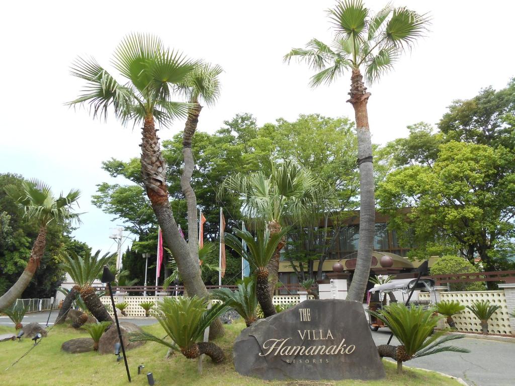 The Villa Hamanako في Kosai: علامة في حديقة مع أشجار النخيل