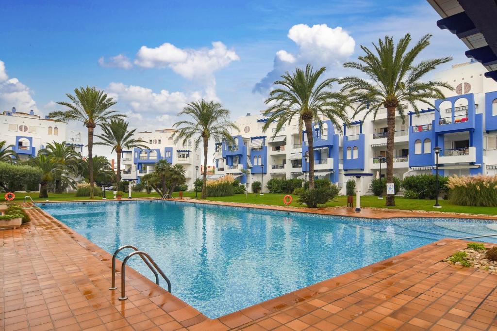 una gran piscina con palmeras y edificios en Els Molins 4, en Denia