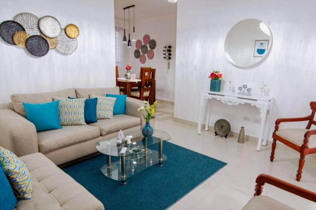 ein Wohnzimmer mit einem Sofa und einem Tisch in der Unterkunft Hermoso apartamento, 3 Habitaciones espaciosas, 2 Aires acondicionados in Santiago de los Caballeros