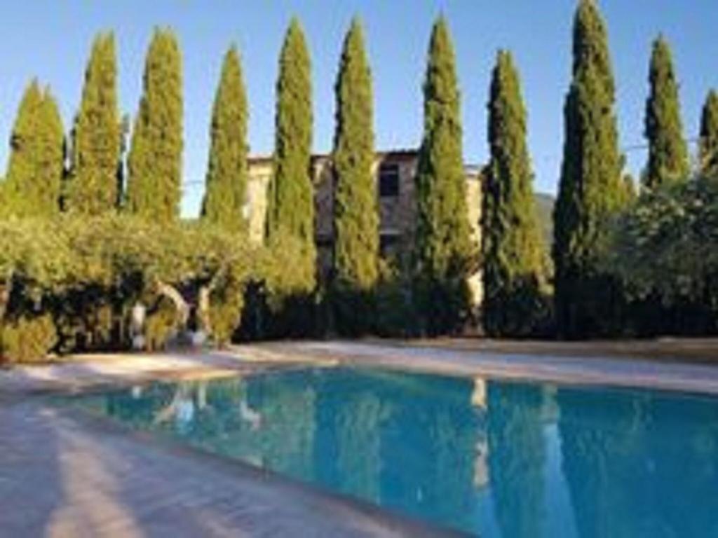 una piscina frente a un edificio con árboles en Belvilla by OYO Casa del Re, en Le Piazze