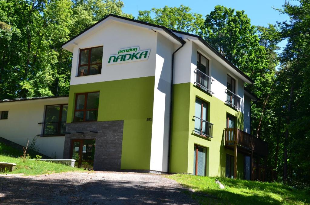 een geel en groen gebouw met een bord erop bij Penzión NADKA in Bojnice