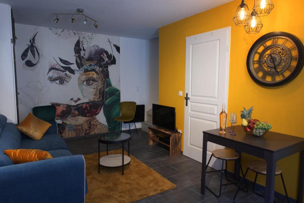 ein Wohnzimmer mit einem blauen Sofa und einem Gemälde an der Wand in der Unterkunft Duplex charmant idéalement situé in Dole