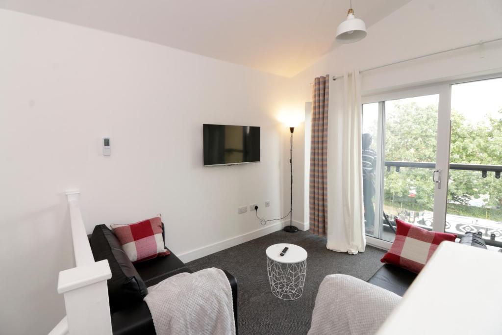 a living room with a couch and chairs and a tv at Canal View Apartment in Bletchley