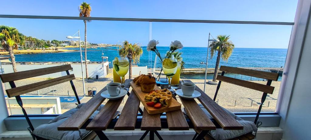 a wooden table with a plate of food and a view of the ocean at Phaedrus Living: Seaview Onyx Flat Lighthouse 48 in Paphos