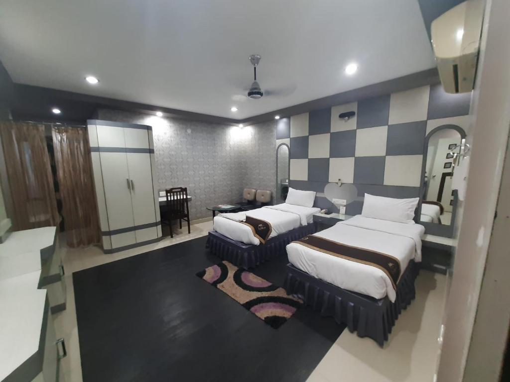 a bedroom with two beds and a checkerboard wall at Hotel Corporate Inn, Patna in Khagaul