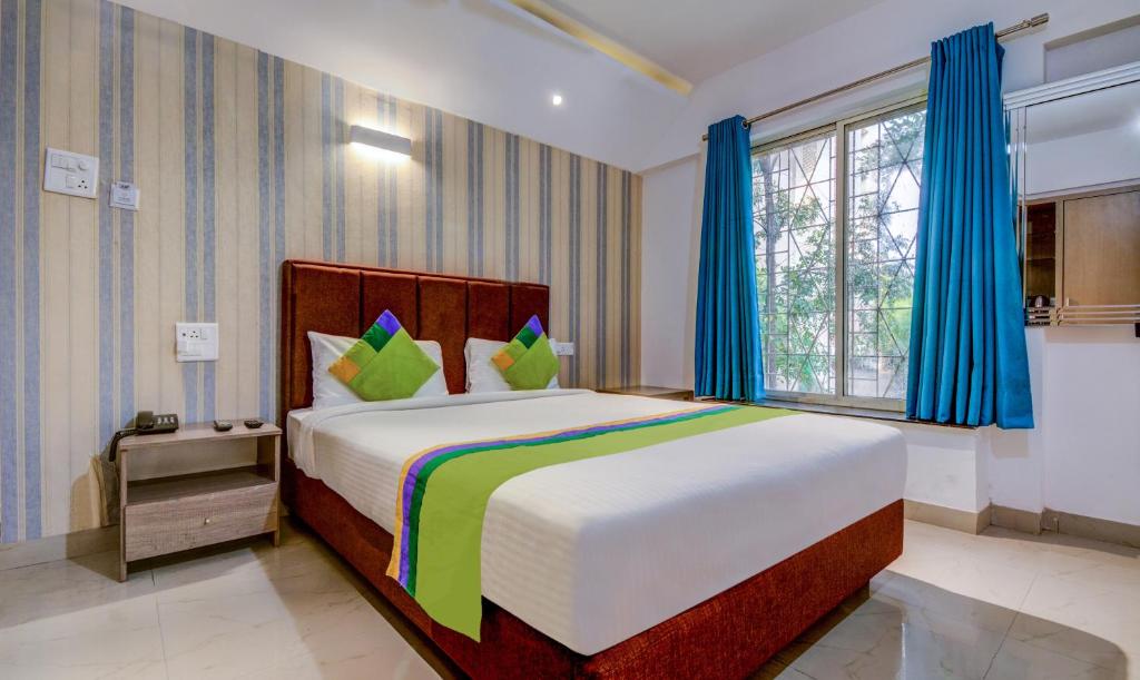 a bedroom with a large bed with blue curtains at Treebo Trend Iris Suites in Pune