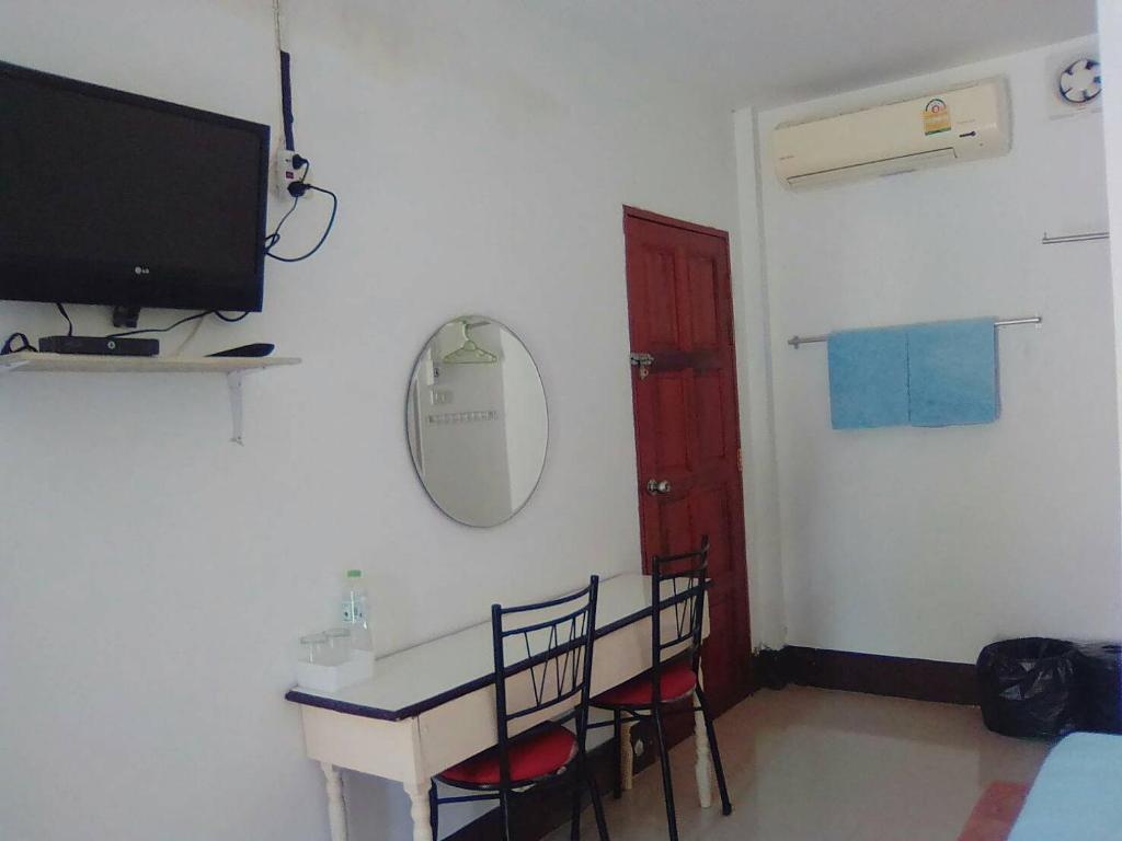 a room with a table and chairs and a television at Thanathorn Guesthouse in Trang