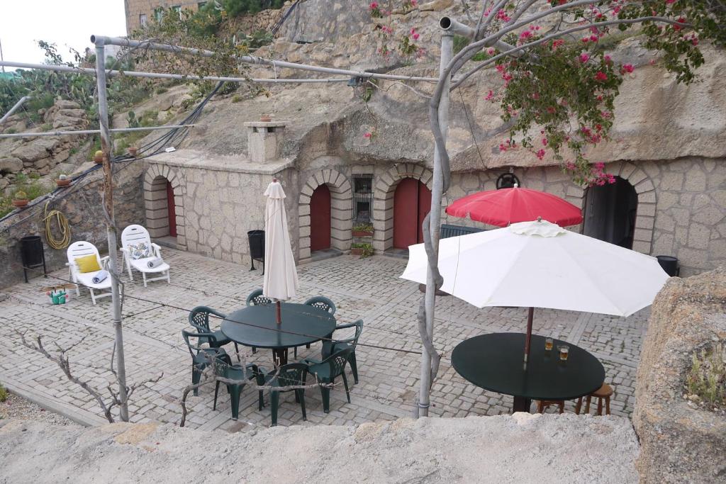 un patio con mesas, sillas y sombrillas en Eco Holidays Cave House Justine, en Granadilla de Abona